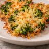 Crispy parmesan smashed broccoli with golden cheese edges on a white ceramic plate