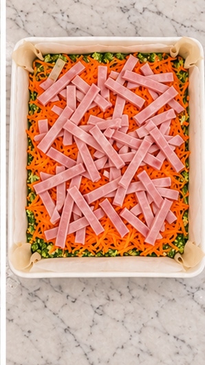 broccoli egg bake chopped broccoli, grated carrots and cooked ham in a lined dish